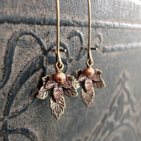 handmade earrings with antiqued bronze and antiqued copper maple leaf charms with a crystal copper pearl dangle.