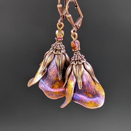 Iridescent Flower Earrings in Pink, Orange, Yellow, and blue with Antiqued Copper metal. The flower earrings are photographed on a black background.