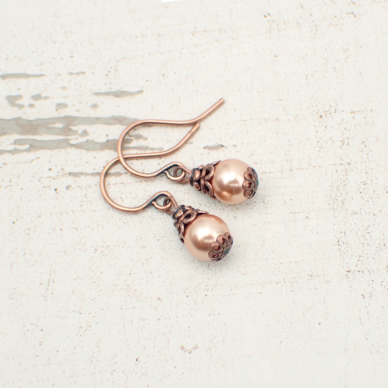 Dainty little rose gold-colored crystal pearls dressed with antiqued copper details.